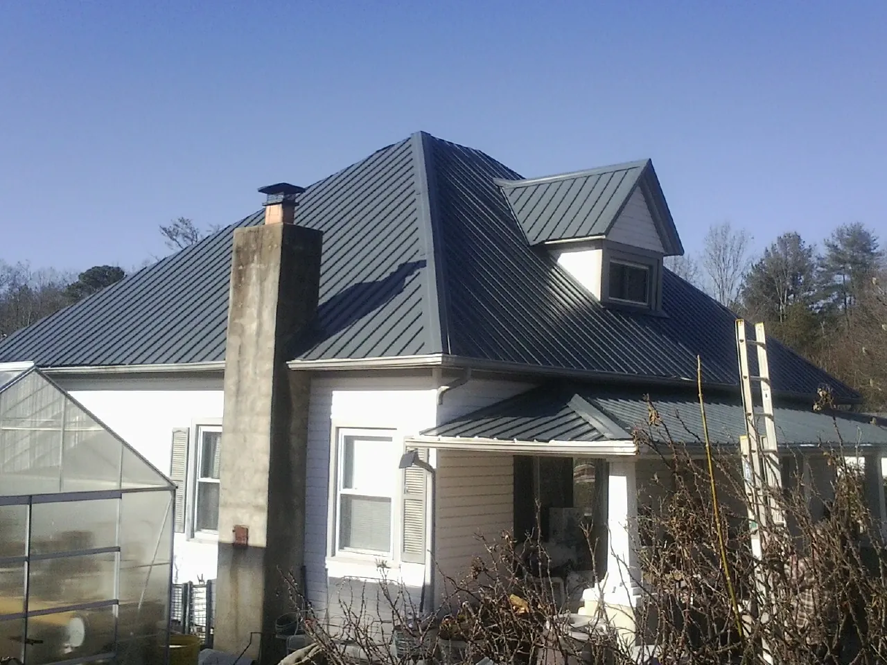Dark blue standing seam metal roof on a white farmhouse with dormer — Slate & Tile Roof Repair by Roofing Brothers in Valley Center