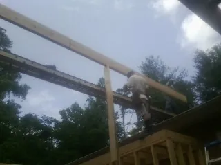 Carpenter setting a ridge beam over a new addition frame — Ice Dam Removal by Roofing Brothers in Valley Center