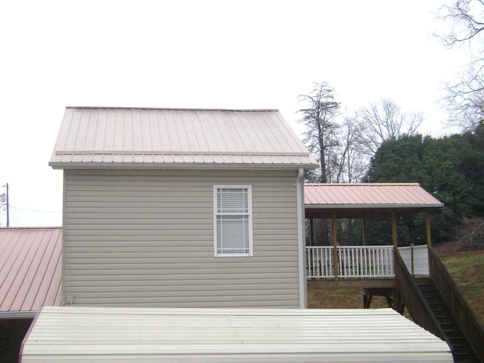 Tan metal roofs on a two story addition and attached porch, from a Roof Replacement job in Valley Center
