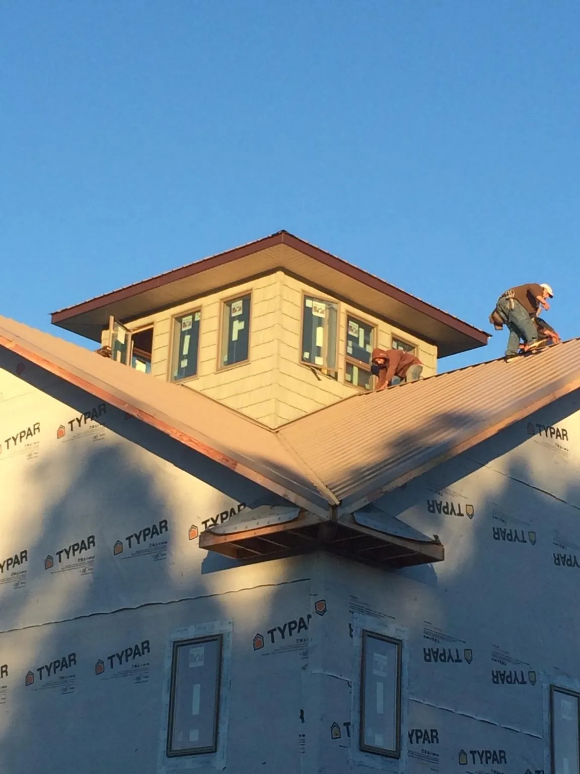 Roofers working around a rooftop cupola on a new metal roof at sunset — Roof Waterproofing in Valley Center by Roofing Brothers